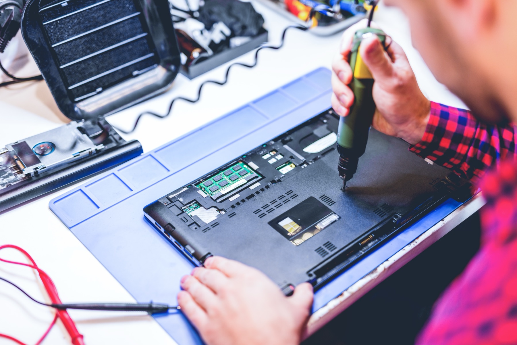 Technician repairing a laptop at a workbench